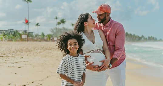 Child in the foreground with parents behind holding baby bump during a maternity photoshoot in Punta Cana near Dreams Macao Beach with Punta Cana photographer