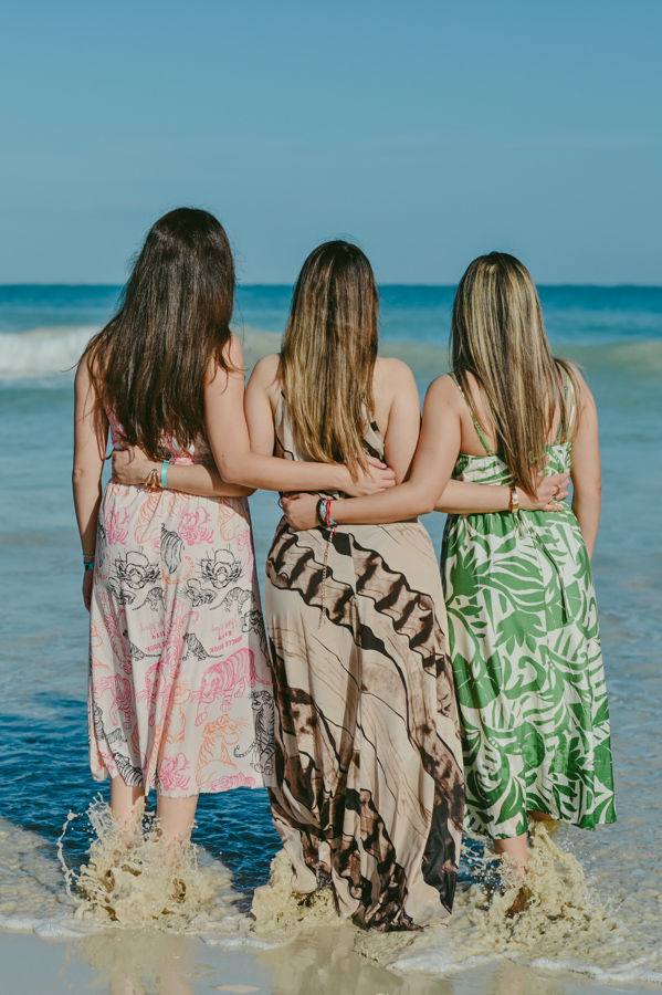 Tres amigas abrazadas de espaldas frente al mar Caribe durante una sesion de fotos de cumpleaños con fotografo en Punta Cana en Playa Macao Republica Dominicana