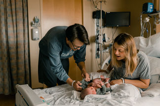 mom and dad changing newborn baby's diaper in the hospital