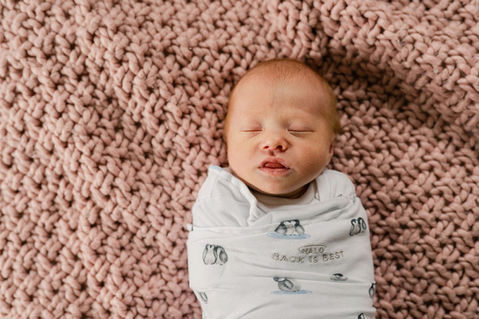 swaddled newborn girl sleeping on a pink blanket