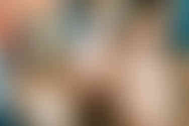 older sibling holding baby's hand near a goat