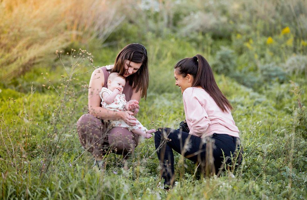 Photographer interacting with a baby during a family photo shoot.