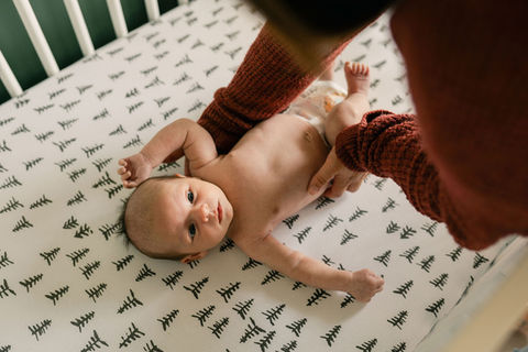 mom placing newborn baby in his crib