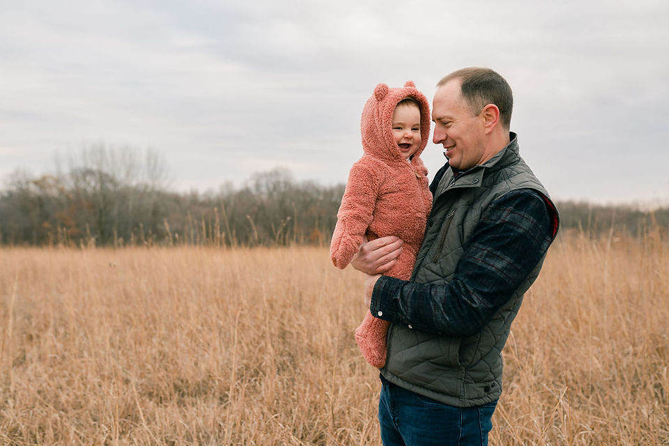 dad holding a baby in a winter snowsuit