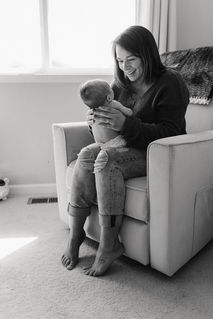 mom holding newborn baby in a nursery chair