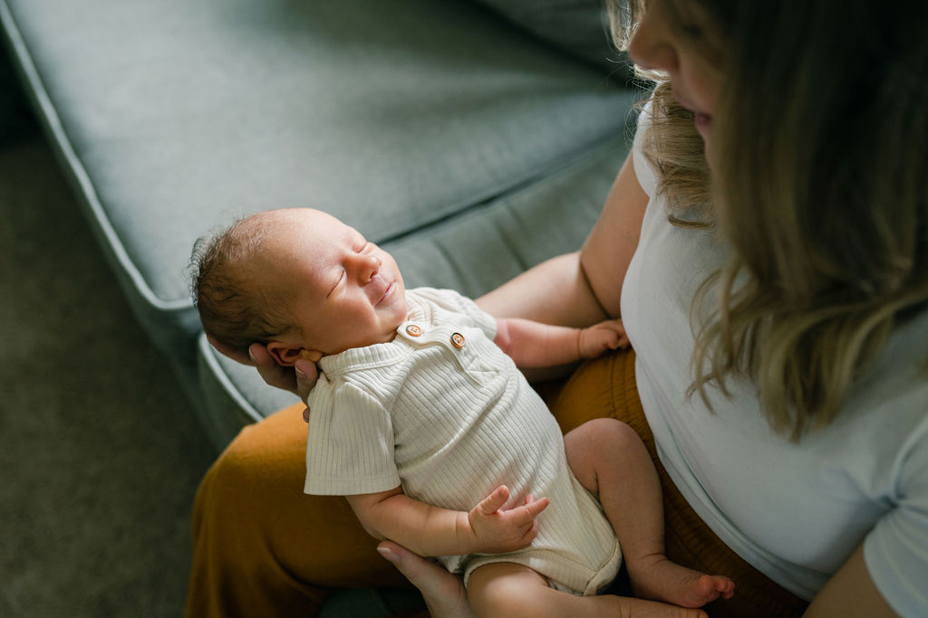 mom holding newborn baby boy on the couch