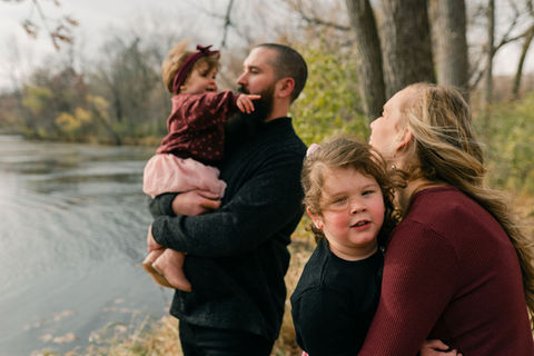 family of four hanging out next to a lake in the fall