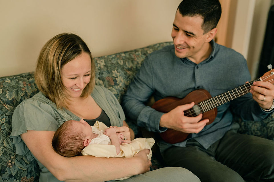 dad playing a song on his guitar for his newborn baby girl
