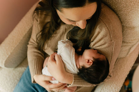 mom holding newborn baby girl on a nursery chair