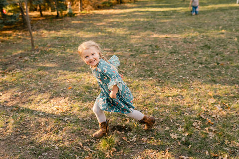 girl in blue dress running in her backyard