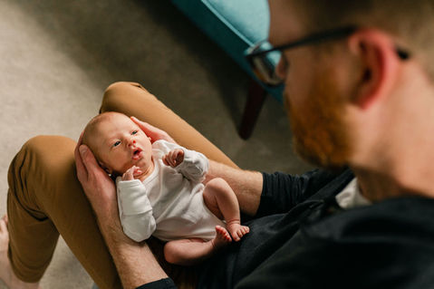 dad holding newborn baby in a white onesie