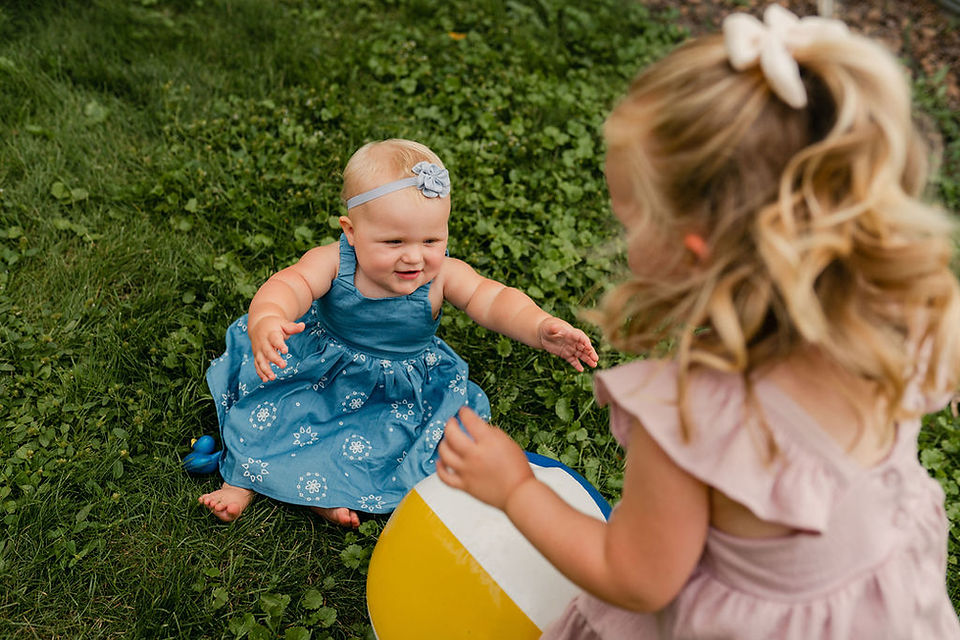 one year old baby and big sister playing with an inflatable ball