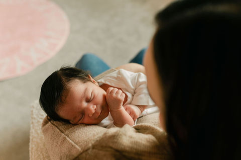 mom holding newborn baby girl on a nursery chair