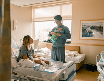 dad opening a package of diapers in a hospital in Maple Grove during fresh 48 Photos