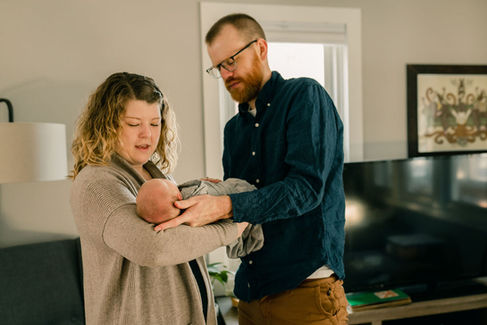 mom passing newborn baby to dad
