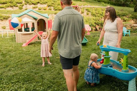family playing with a water table and beach ball in their backyard