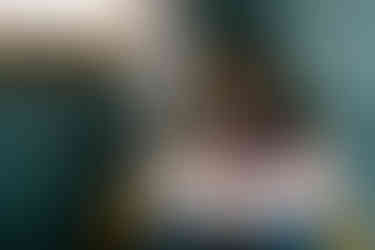 mom nursing newborn baby in a chair next to a window