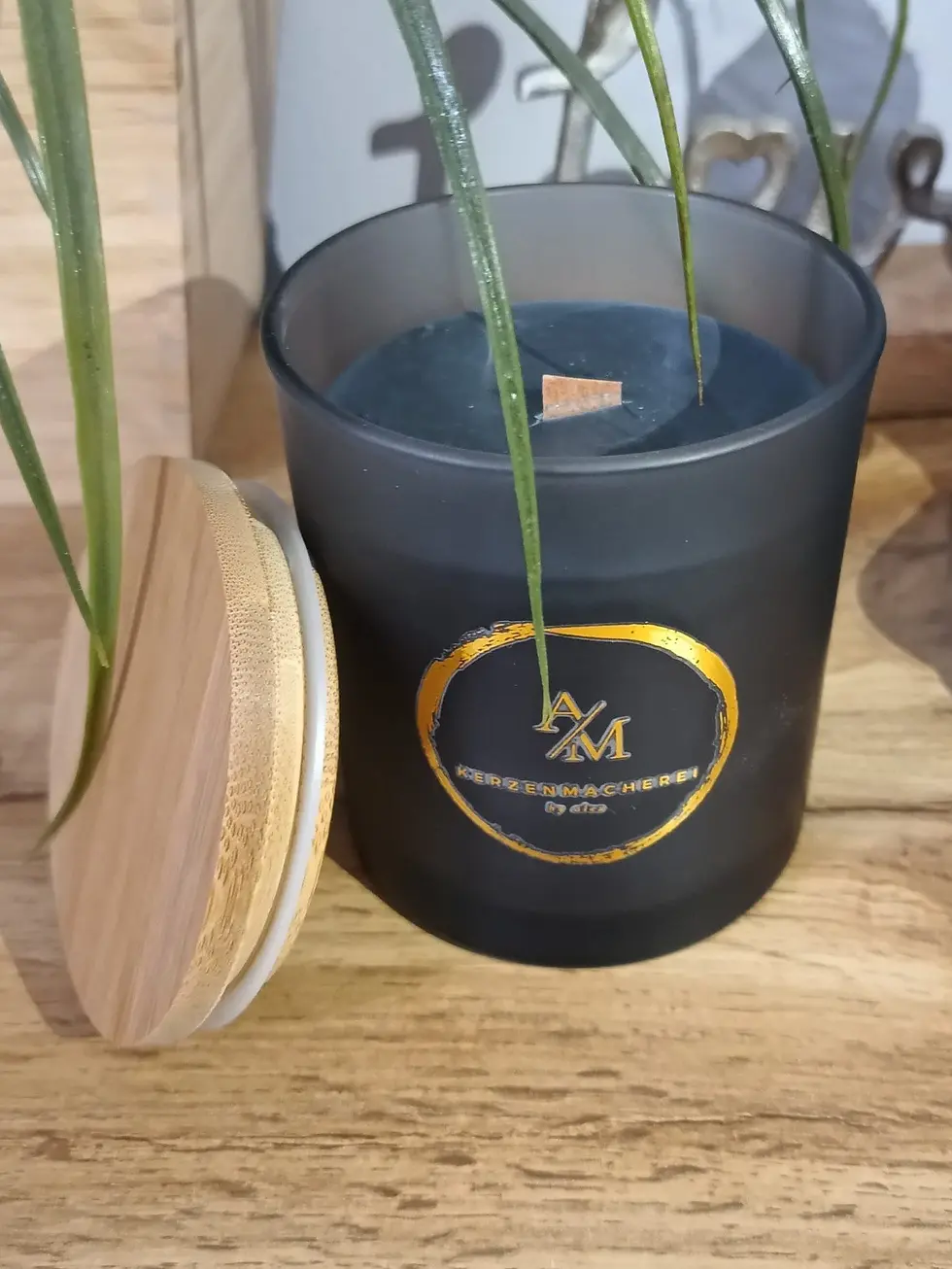 Miniaturbild: Schwarze Kerze "N/M" mit Deckel und goldener Aufschrift, Dekovision.