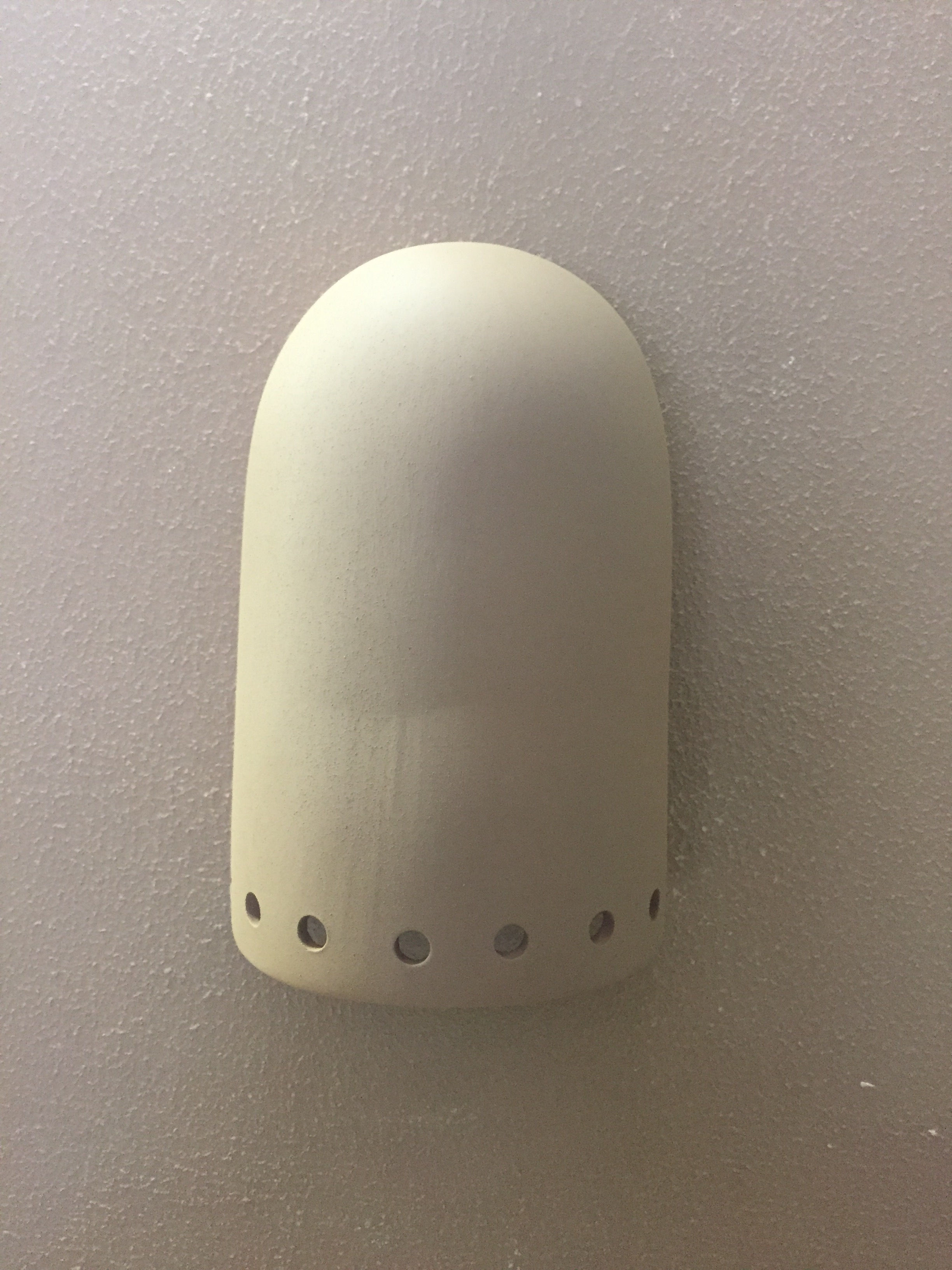 Dome light wall sconce with small holes on the bottom, hanging on the wall.