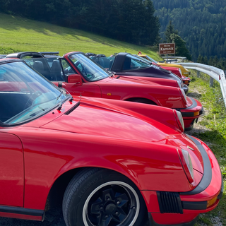 sideview of front part of red Porsche 911 with multipe Porsche in the back