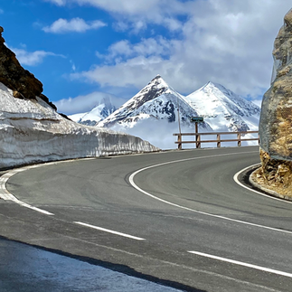 curvy street with snow-covered mountains in the back