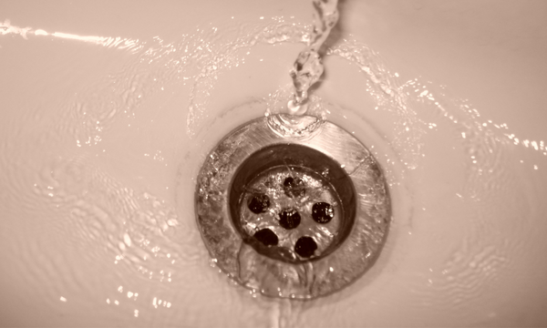 All Pro plumber using auger to clear clogged bathroom drain