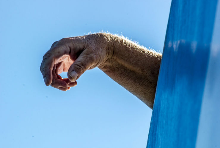 Wide angle low light photo of a focused athlete chalking his hands before attempting a bar swing in a gym environment.