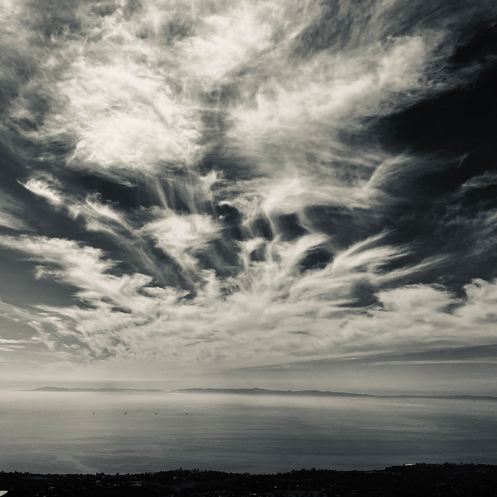 Monochrome view of wispy cirrus clouds above a distant ocean horizon. Santa Barbara Channel and Channel Islands. 