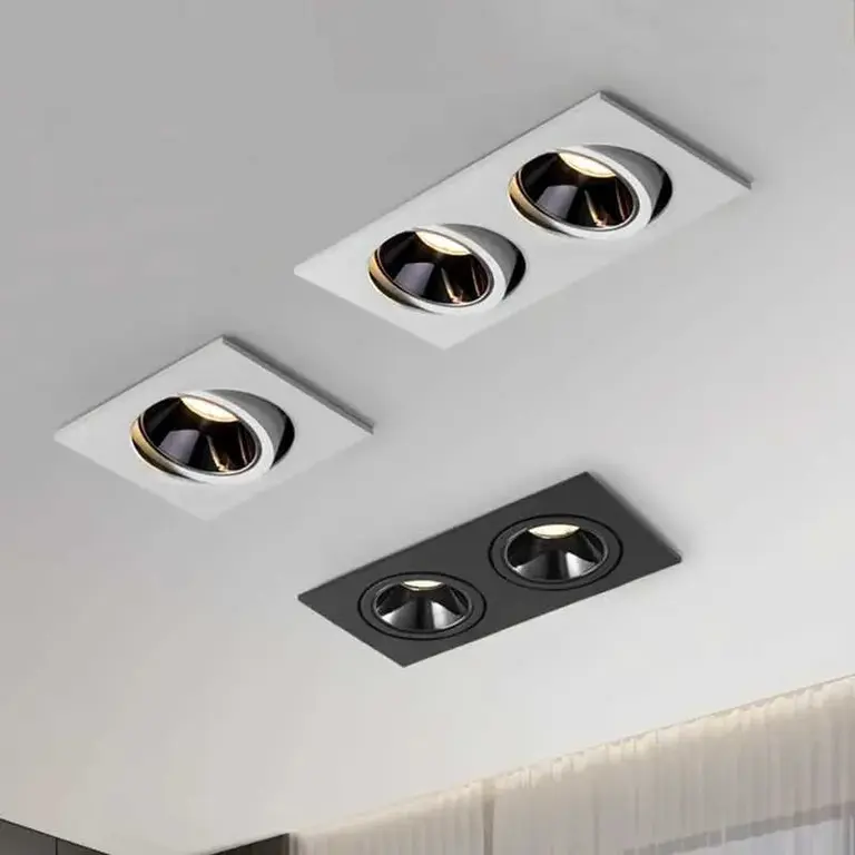 Gri tavanda yer alan, ikili ve üçlü modern spot aydınlatma armatürleri, beyaz ve siyah kasalı, kare formlu, içi siyah reflektörlü, dikdörtgen kadraj, iç mekan aydınlatma ürünü tanıtım fotoğrafı.
