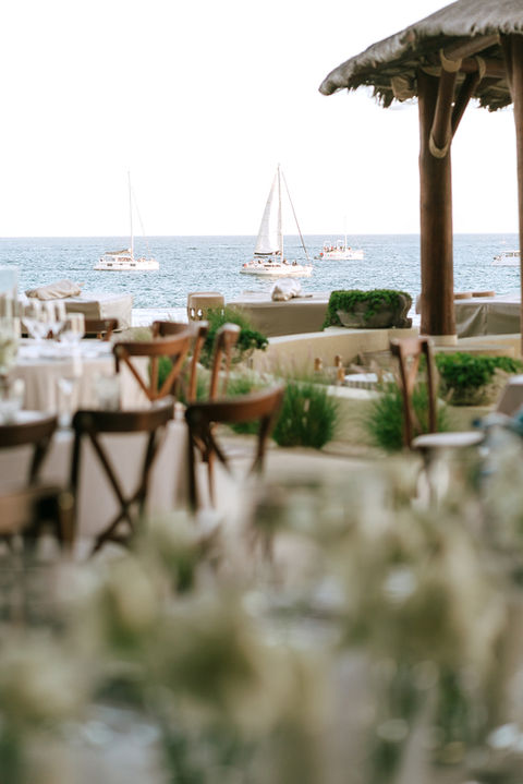 Oceanfront wedding reception setup with sailboats in the distance.