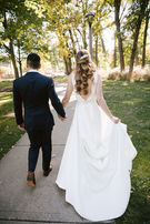 Bride and groom walking away together, bride holding train of gown.