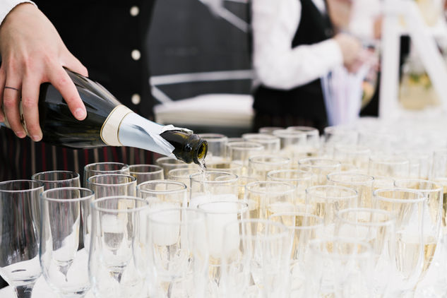Bartender pouring champagne into glasses for a wedding celebration.