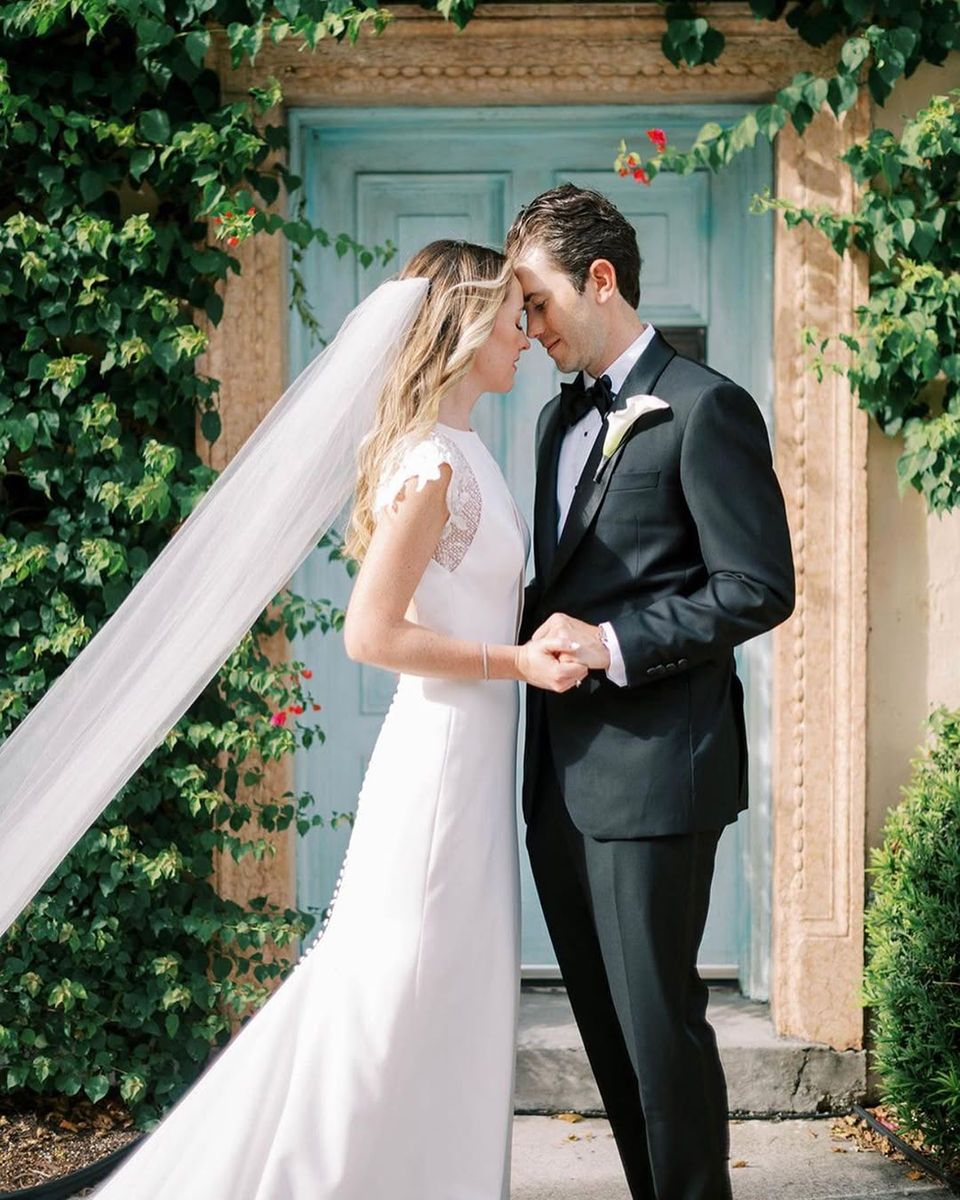 Bride and groom embracing in front of ivy-covered doors in South Florida.