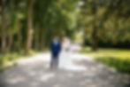 Bride and groom walking hand in hand down a tree lined path after their wedding, featuring soft bridal hair and makeup by CampBride.