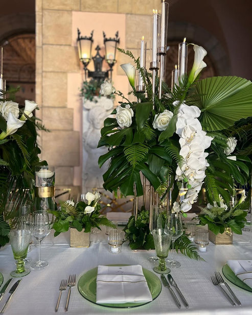 Green and white floral wedding table design with modern glass details.