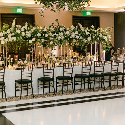Long reception table lined with tall floral arrangements and candlelight.