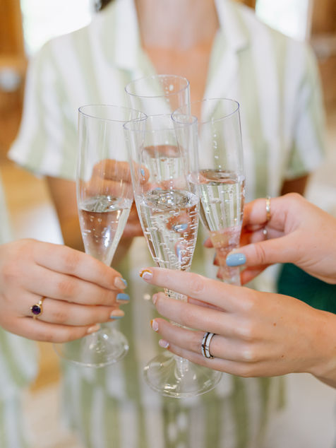 Close up of hands clinking champagne glasses during wedding day getting ready.