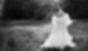 A bride in a flowing gown standing in a field, soft light, romantic, elevated, editorial feel.
