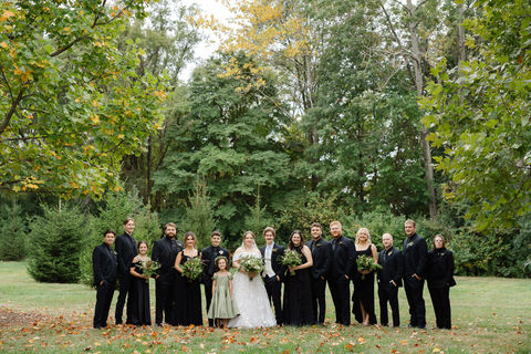 Wedding party standing together outdoors surrounded by greenery with cohesive hair and makeup styling.