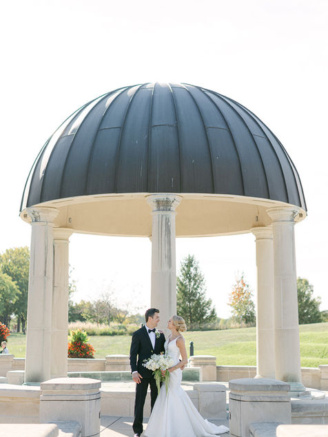 Bride and groom seated together under a domed gazebo during portraits.