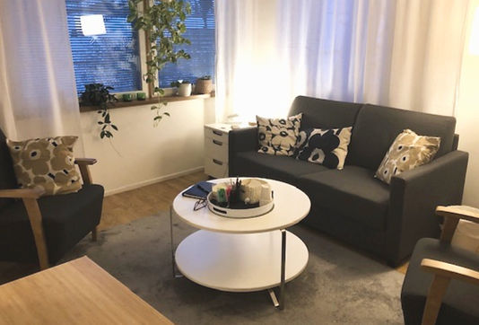 Terapeutin vastaanotto. Kuvassa kaksi sohvaa ja sohvapöytä keskellä huonetta.
