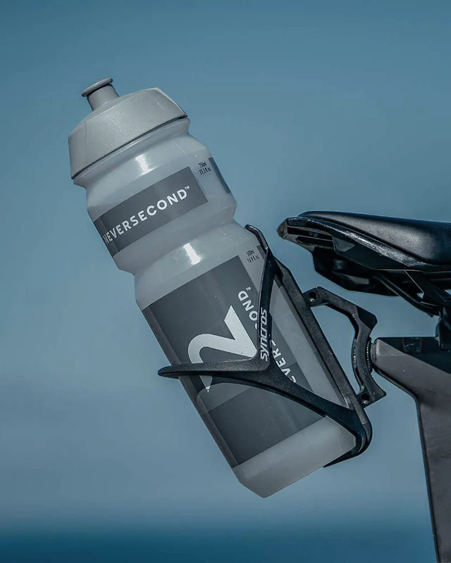 Gray water bottle labeled "NEVERSECOND" in a black holder on a bicycle against a blue sky background.
