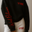 Thumbnail: Model wearing black VYBE sweatshirt with red “Worst Behavior” embroidery on sleeve and white joggers with red logo.