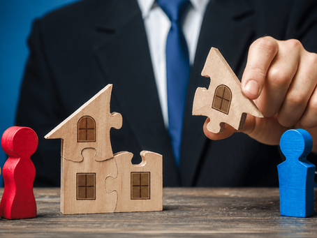 Attorney separating pieces of a wooden house puzzle between two people, symbolizing property division during divorce.