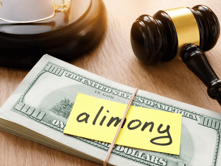 Judge’s gavel and stack of cash labeled “alimony” on a desk beside eyeglasses, representing legal financial support after divorce.