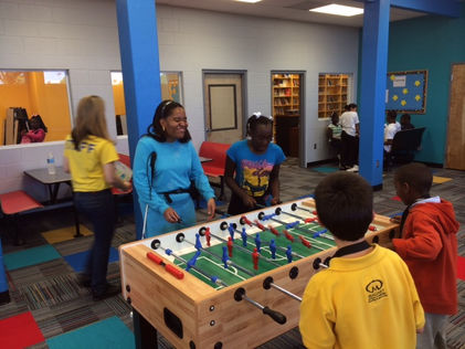 Conklin Davis Center for The Visually Impaired Teen Transition program members play a game of foosball with a pair of younger boys in an arcade room