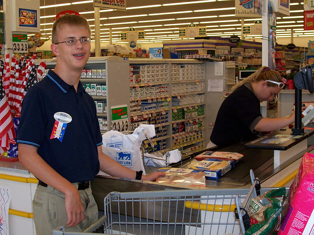 A visually impaired boy serves customers at a checkout counter