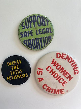 Three badges reading: "Support safe legal abortion", "Defeat the fetus fetishists", "Denying women choice is a crime".