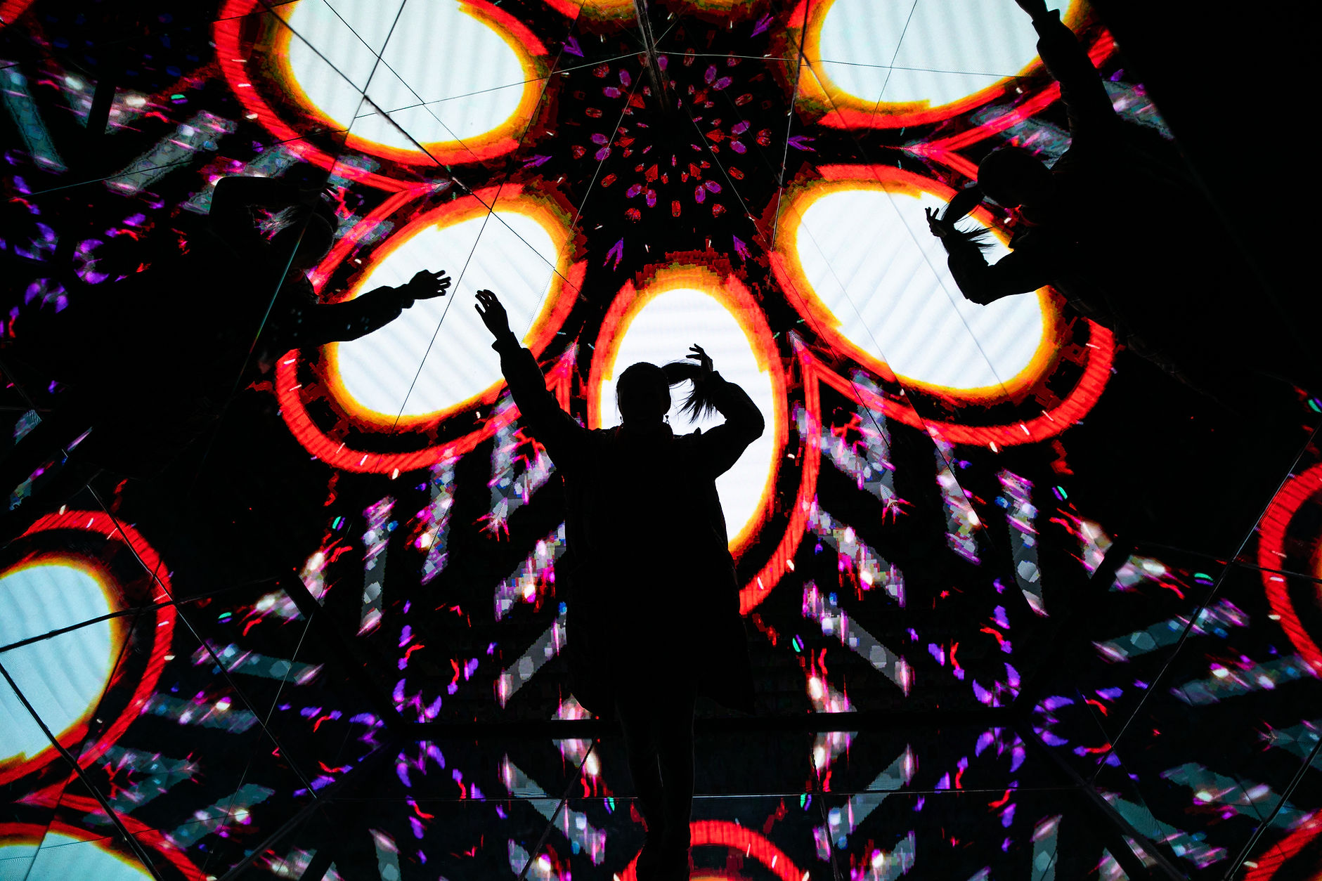 Silhouetted figures dance before vibrant light display