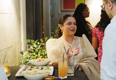 Woman in traditional Filipiniana dress engages in conversation at corporate event.